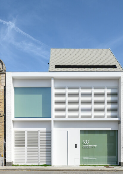 Moderne praktijkwoning met wit gevelkader en sculpturaal dak