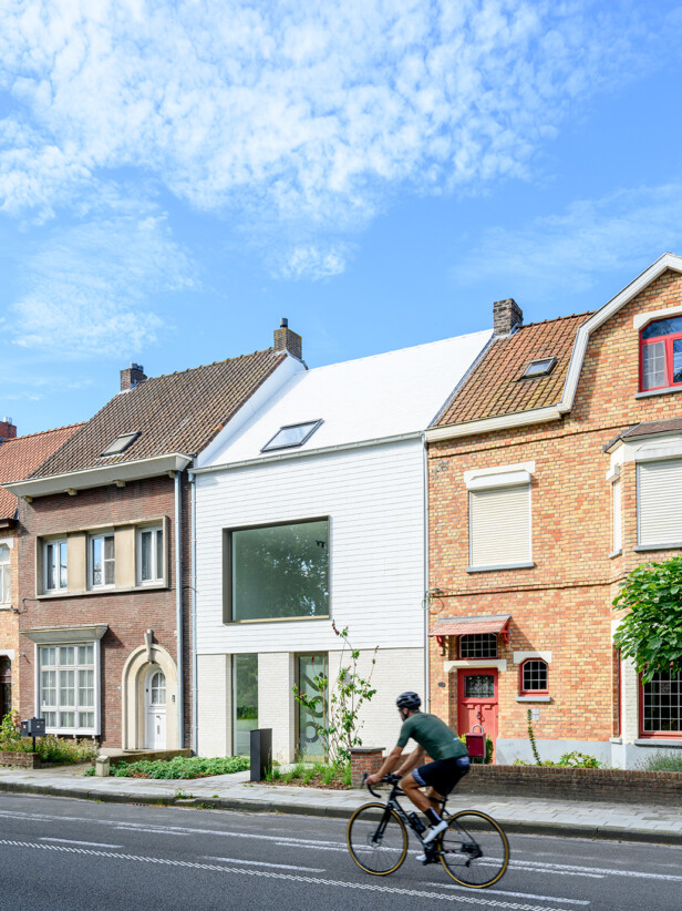 Moderne witte rijwoning met groot panoramaraam en fietser in straatbeeld